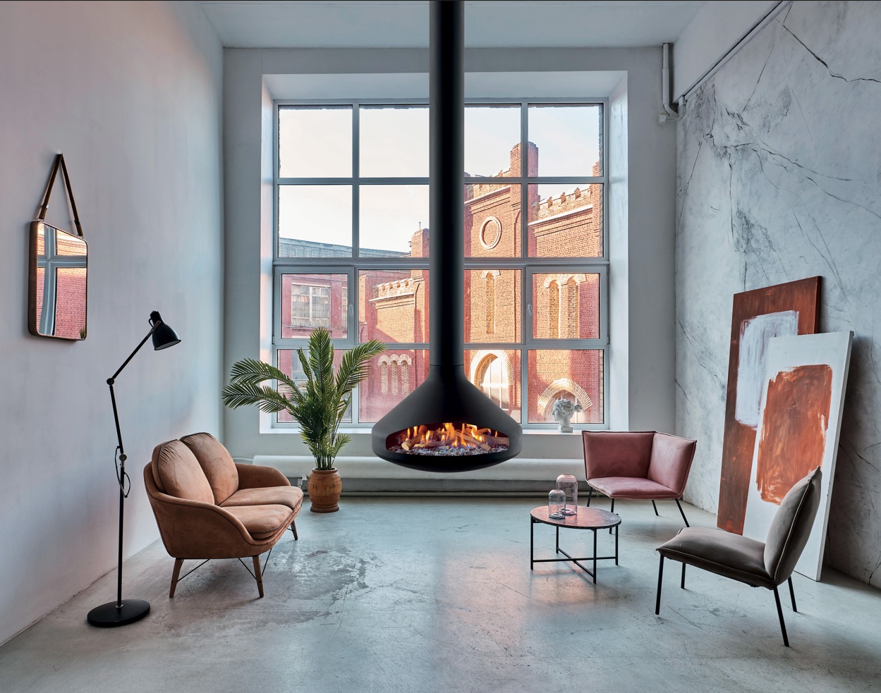 Focus Ergofocus suspended steel fireplace pivoting freely at the centre of a modern interior, an angular folded-steel hood hung from a single column over an open hearth