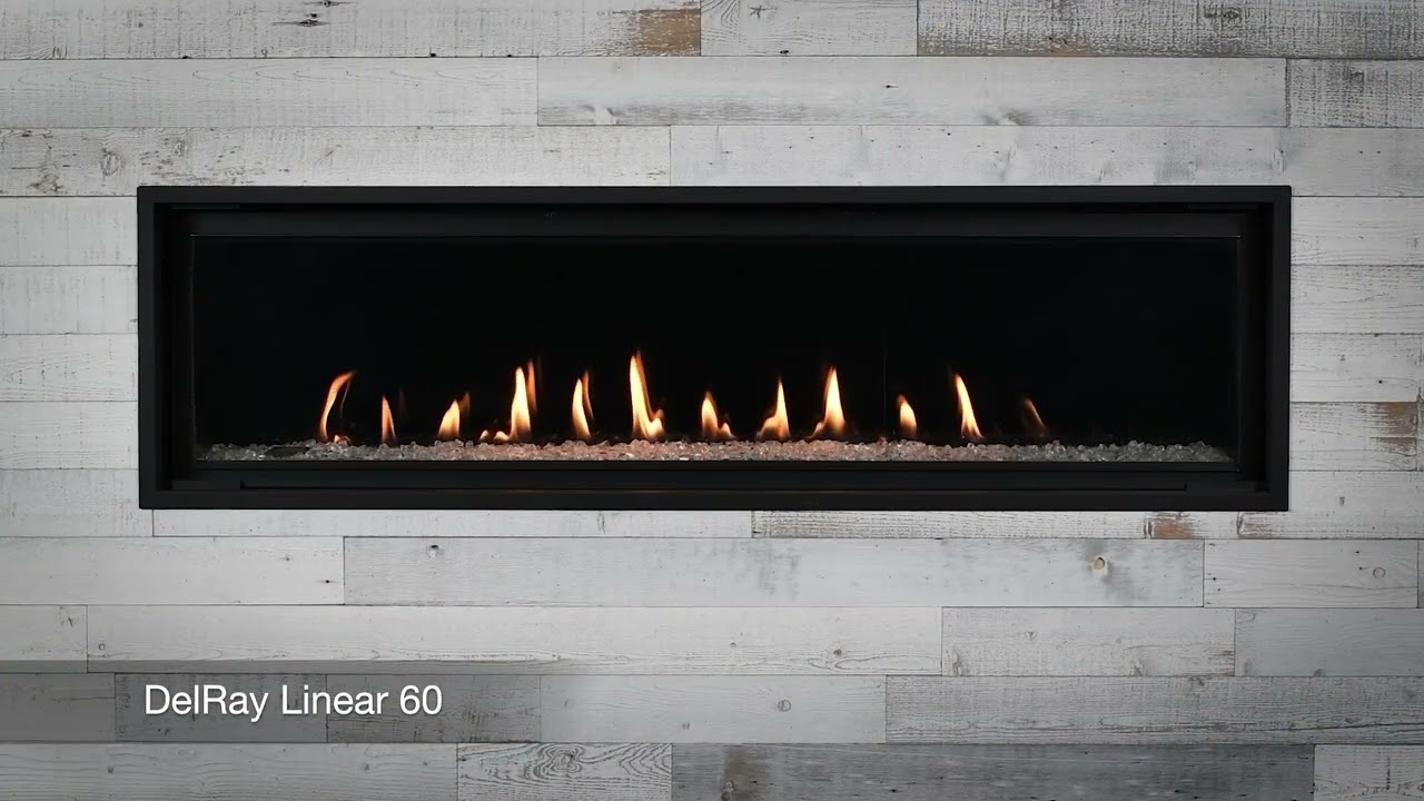 Montigo DelRay Linear 60 gas fireplace, a wide frameless ribbon of flame over a crushed-glass bed, set into a whitewashed reclaimed-plank feature wall