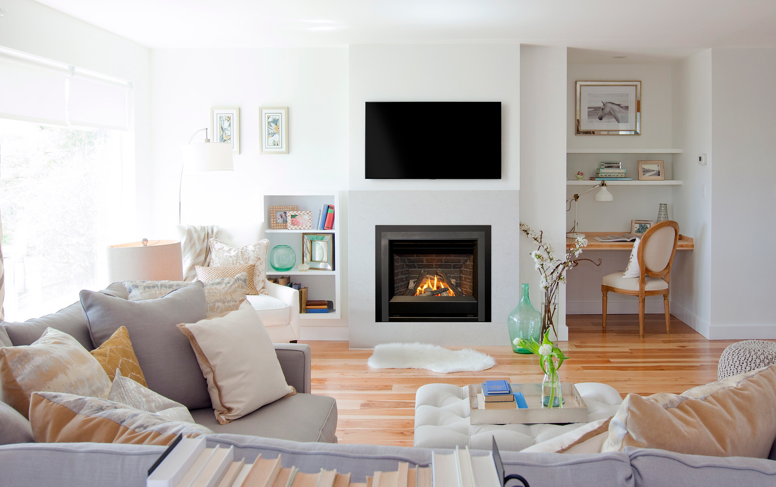 Valor H Series radiant gas fireplace lit beneath a wall-mounted television in a bright, airy living room with neutral sofas and a built-in desk nook