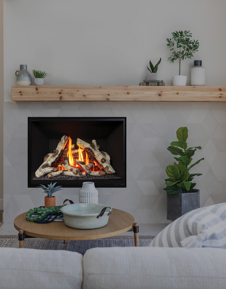 Valor H5 radiant gas fireplace with a tall birch flame set into a pale tile wall beneath a timber mantel