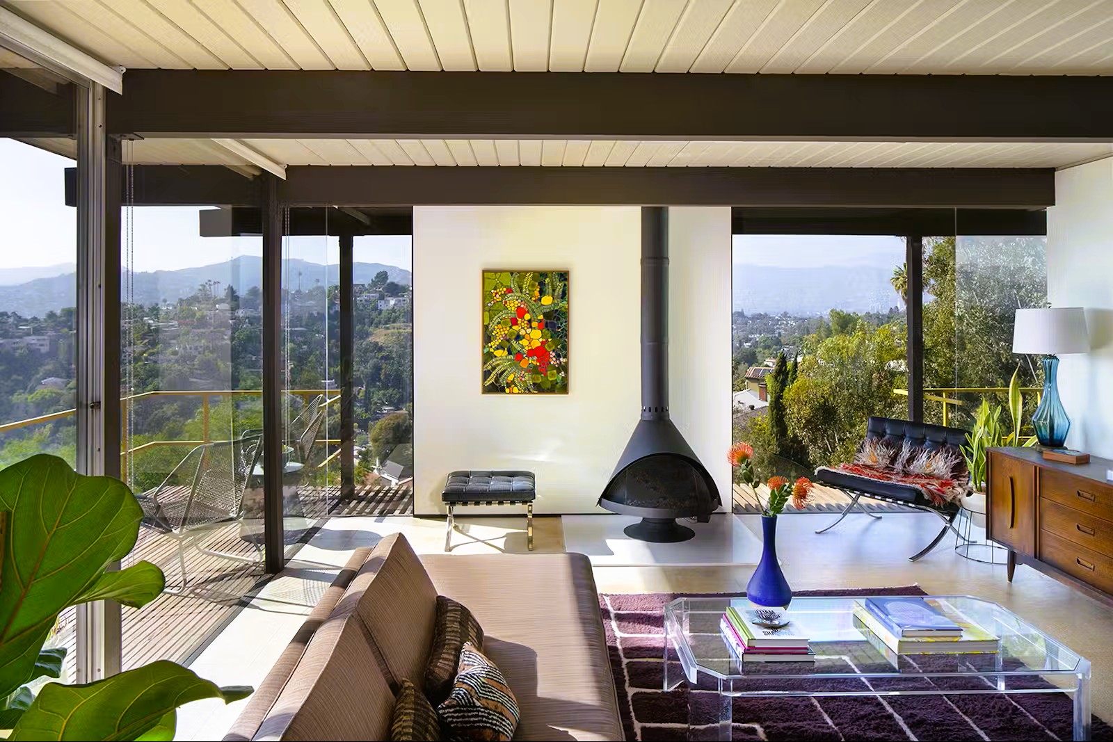 Malm 34 Zircon DV cone fireplace in a mid-century hillside living room with floor-to-ceiling glass overlooking a canyon, Barcelona chairs and a wood-beam ceiling