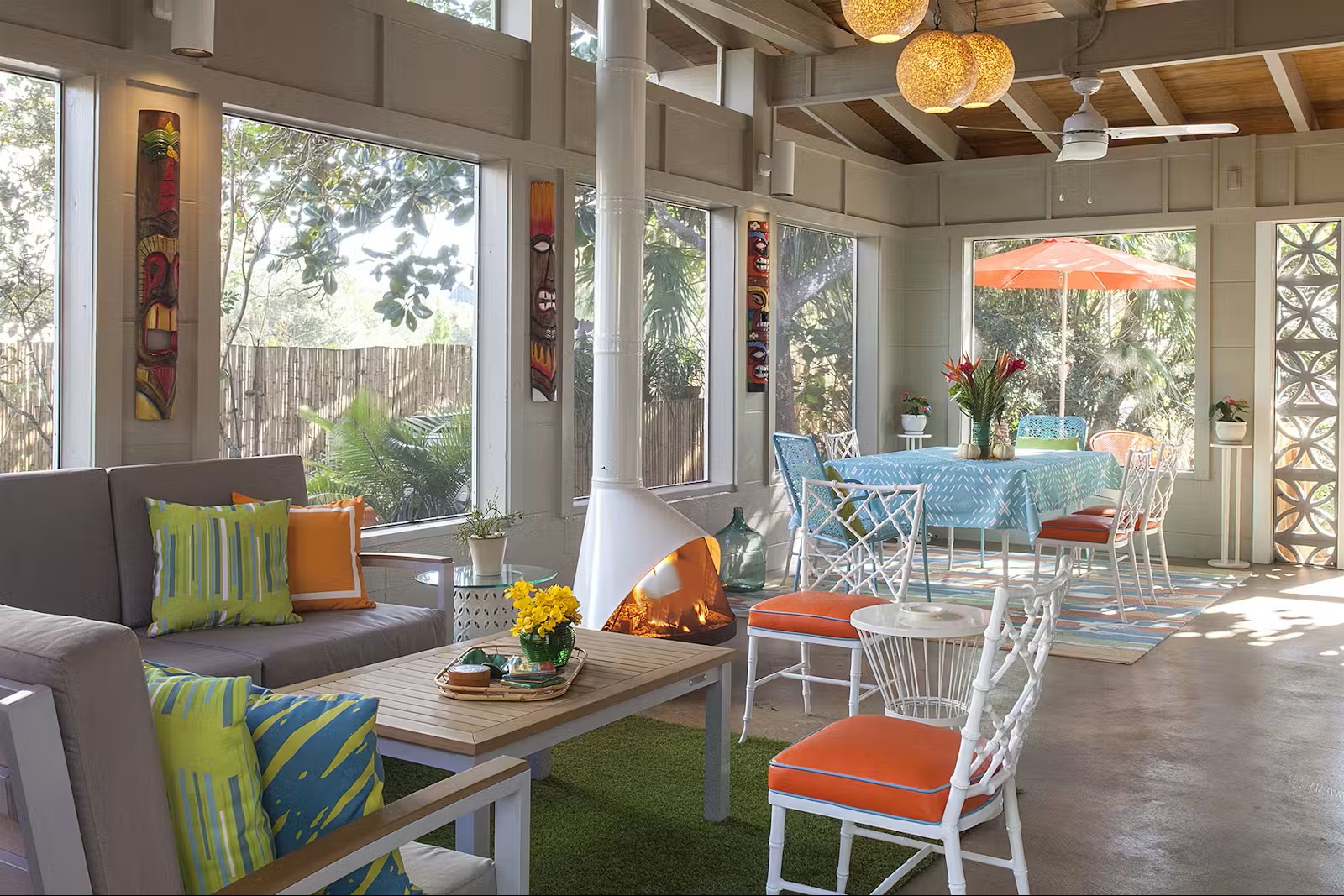 Malm 34 Zircon DV cone fireplace with a lit fire visible inside, in a screened tropical porch with tiki masks on the columns and colourful pillows on the sofa
