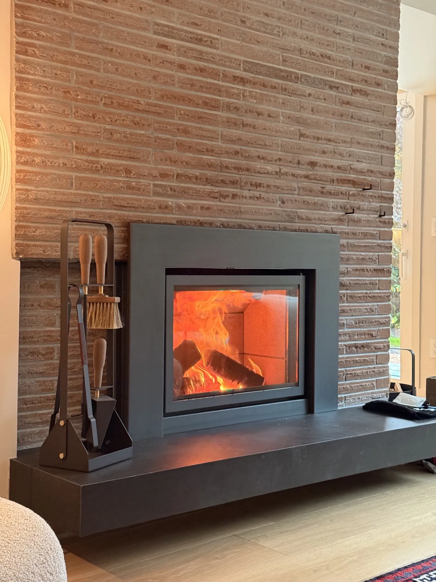 Stûv 16-In set into a custom linear terracotta brick wall with a black steel surround and floating black hearth