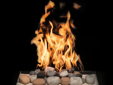 Town & Country Tranquility burner: a tall flame rising from a bed of smooth grey and sand-coloured river stones