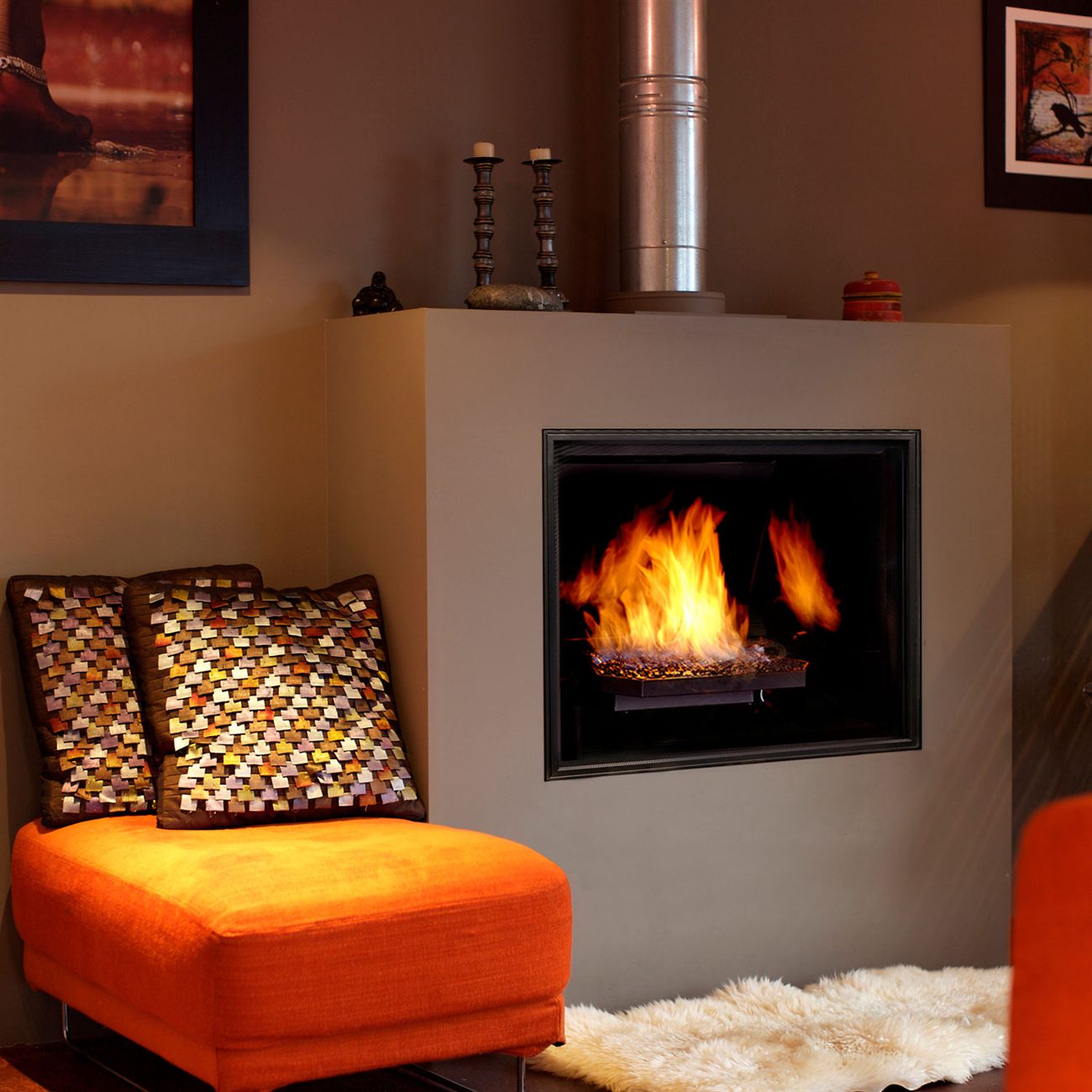 Town & Country TC42 gas fireplace with the Diamond crushed-glass burner and black porcelain panels, tall flames in a clean-faced opening set into a plain taupe chimney breast beside an orange chaise and a sheepskin rug