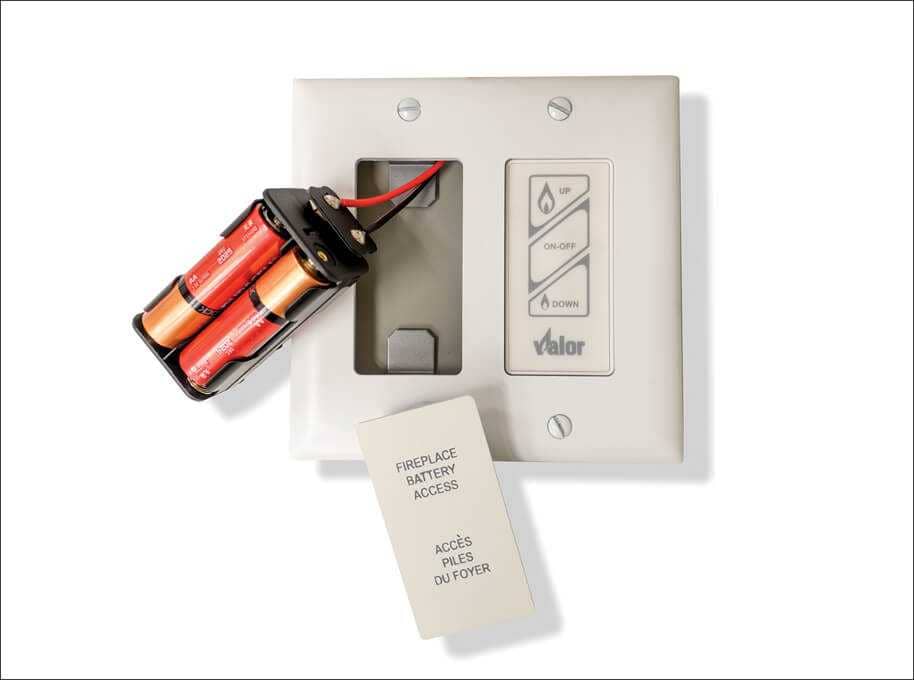 A Valor wall switch with its magnetic Fireplace Battery Access plate removed and the battery holder drawn out beside it