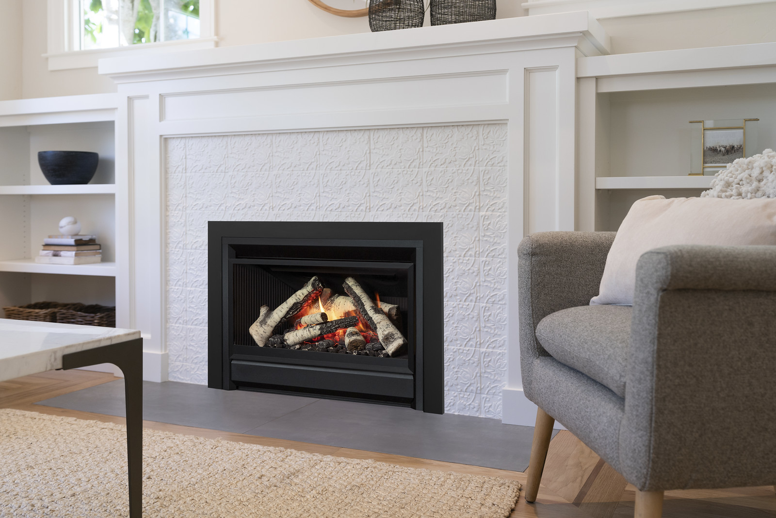 Valor G3 V-Class gas insert with a birch log set and black trim, framed by a white Craftsman mantel and built-in shelves