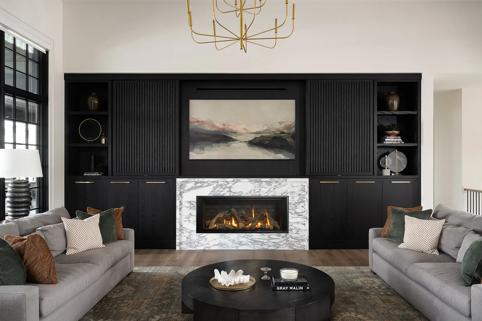 Linear gas fireplace with marble surround, framed art television mounted directly above, vent slot integrated above the marble