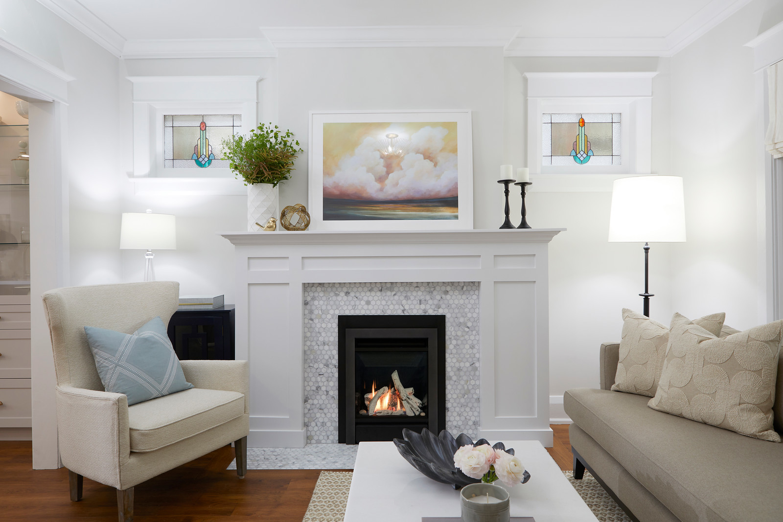 Valor Portrait gas fireplace with a frameless Clearview front set in a bright Craftsman living room with a hex-marble surround, stained-glass transom windows and a cloud painting above the mantel