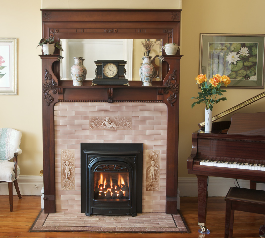Valor Portrait with a black arched President front set into an antique Victorian wood mantel with cherub-relief tile, beside a grand piano