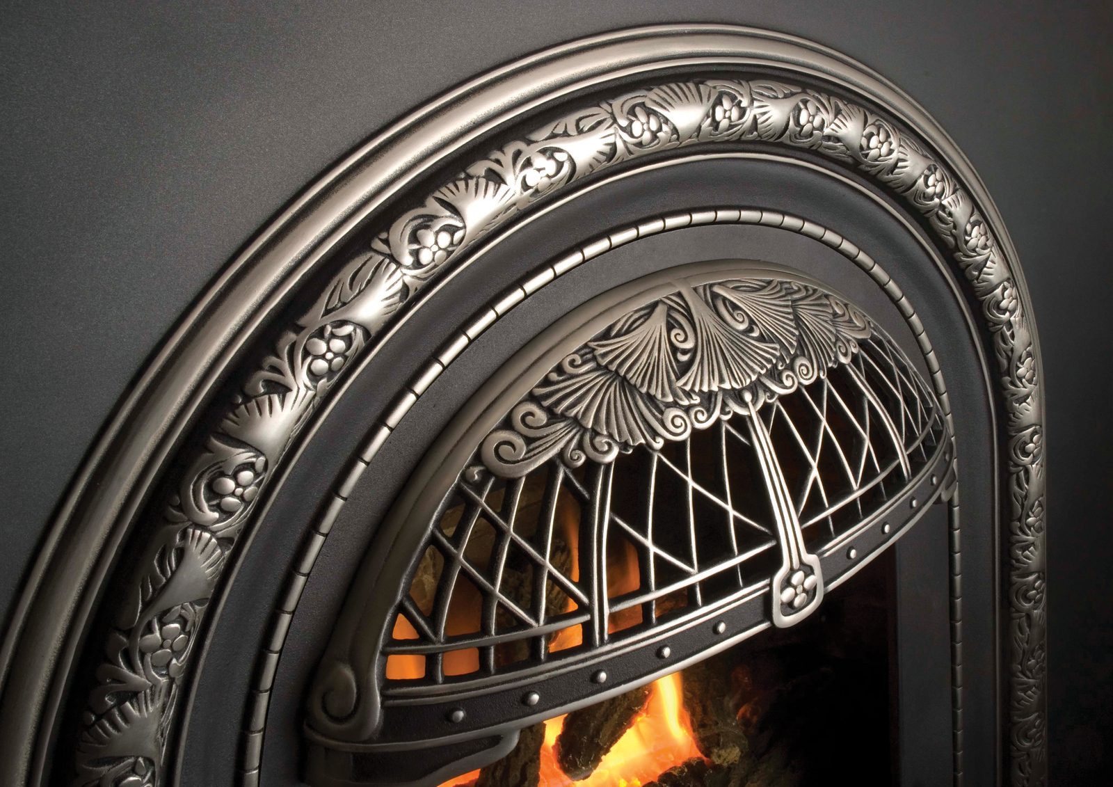 Macro detail of the Valor Portrait Windsor Arch cast front, showing the ornate pewter Art Nouveau fan motif and floral relief with the fire glowing behind