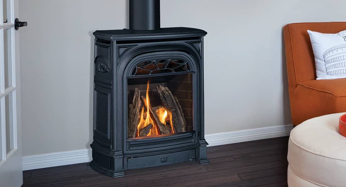 Valor President cast iron gas stove, arched and panelled with a fretwork crest above the glass and a log fire inside